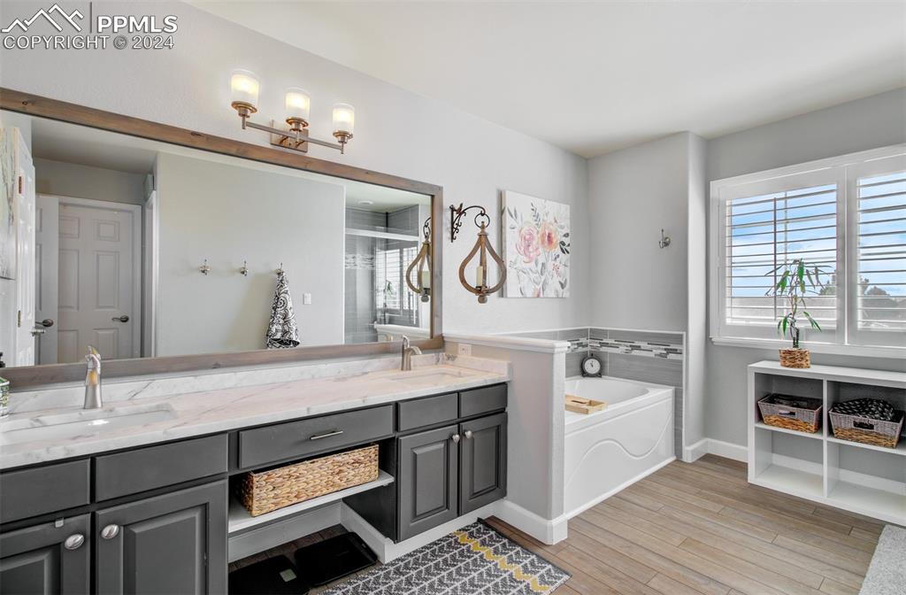 12110 Lazy E Road Peyton, CO 80831 - Photo 16 of 50 a spacious bathroom with a granite countertop sink a large mirror and a bathtub