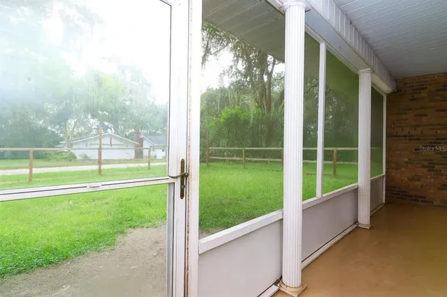 a view of a room with a big yard and large trees
