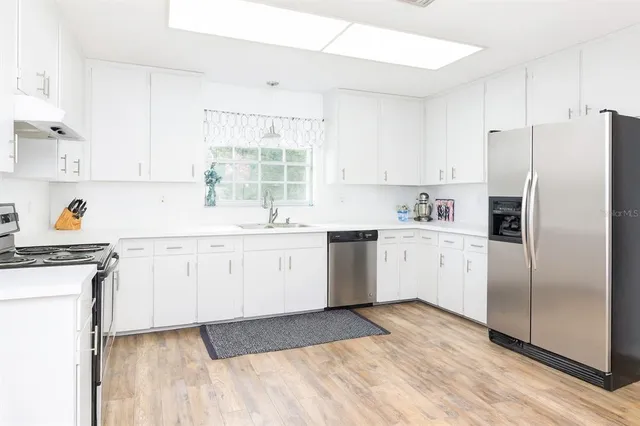 a kitchen with a sink a refrigerator and white cabinets