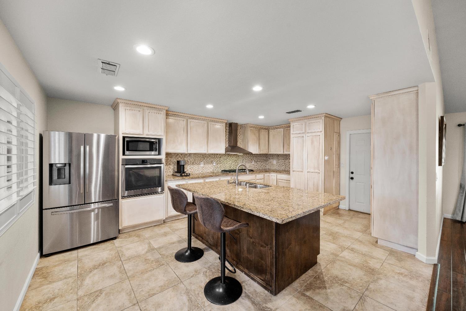 2768 Butte House Road Yuba City, CA 95993 - Photo 12 of 43 a kitchen with stainless steel appliances kitchen island granite countertop a refrigerator and a stove top oven