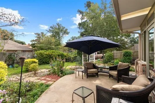 a view of patio with chairs and table under an umbrella