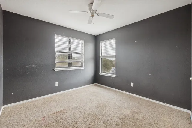 en empty room with windows and ceiling fan