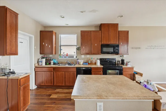 a kitchen with granite countertop a stove top oven a sink dishwasher and wooden cabinets