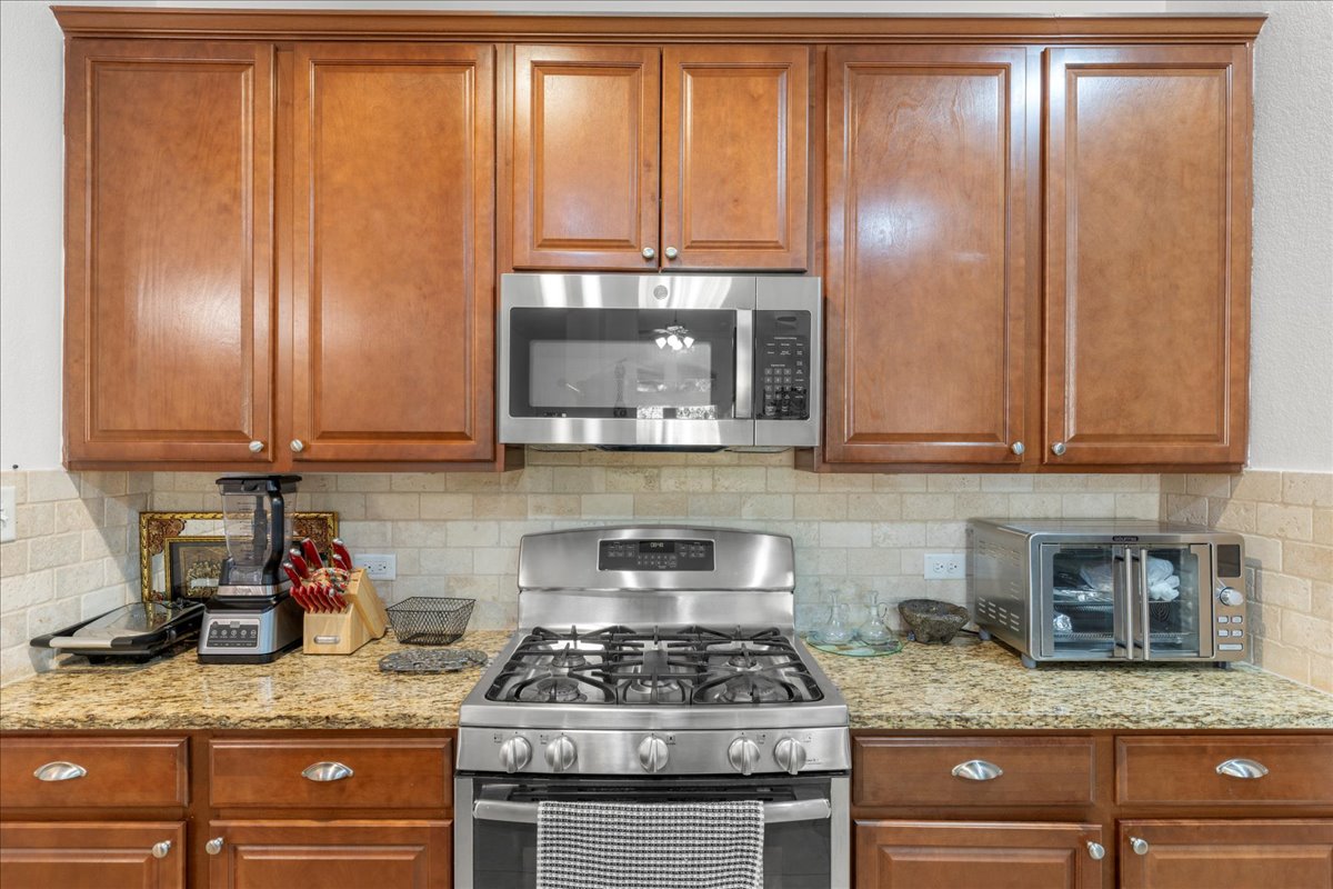 349 Razzmatazz Trail Buda, TX 78610 - Photo 28 of 40 a kitchen with granite countertop stainless steel appliances a stove window and cabinets