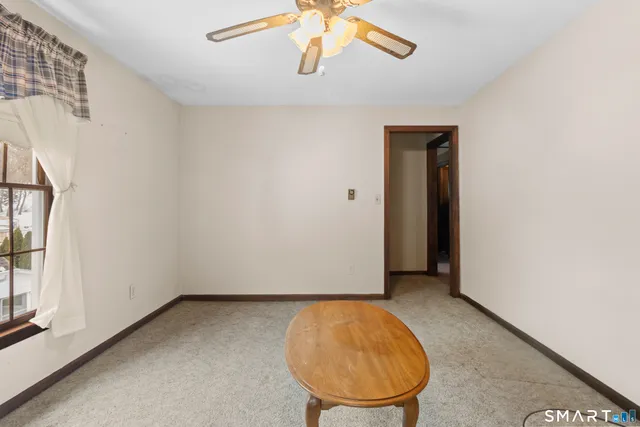 an empty room with a chandelier fan and windows