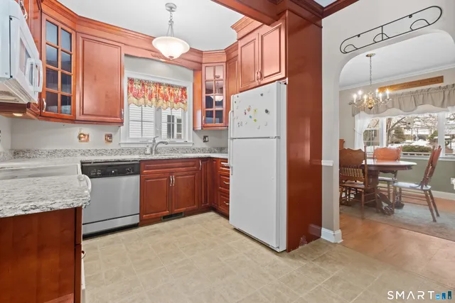 a kitchen with a refrigerator a sink dishwasher a stove and a dining table with wooden cabinet