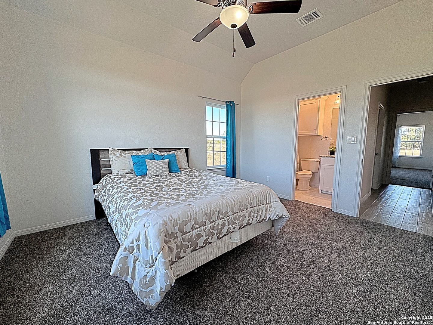 469 Buckskin Trail Bandera, TX 78003 - Photo 11 of 13 a spacious bedroom with a bed and a chandelier