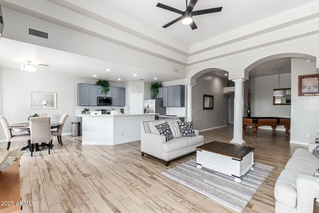 a living room with couches and kitchen view with wooden floor