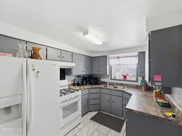 a kitchen with a sink dishwasher a refrigerator and a stove with white countertops