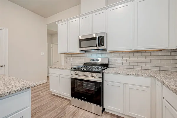 a kitchen with granite countertop cabinets stainless steel appliances and wooden floor