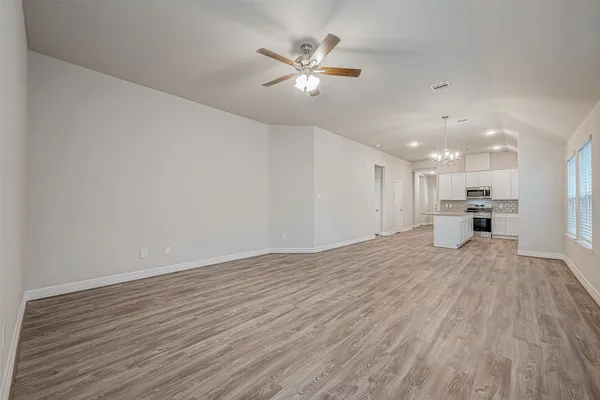 a view of an empty room with a ceiling fan and wooden floor