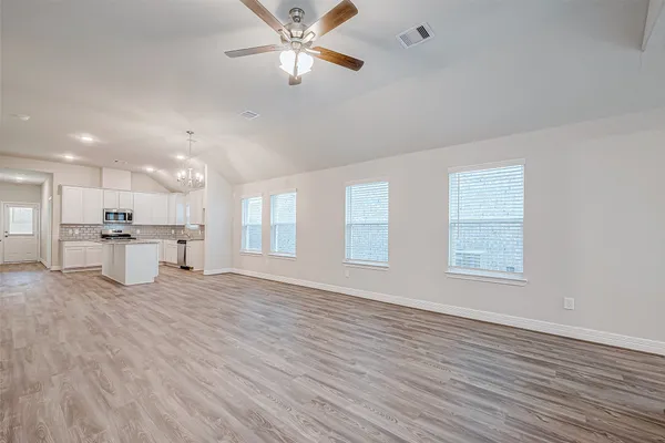 a view of an empty room with window and wooden floor
