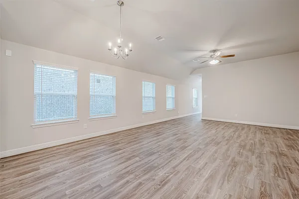 a view of an empty room with a window and wooden floor