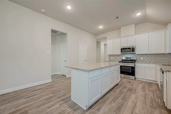 a kitchen with granite countertop a stove top oven and cabinets