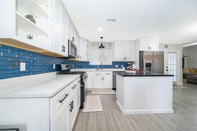 a kitchen with stainless steel appliances granite countertop a white cabinets a sink a stove a dining table and chairs