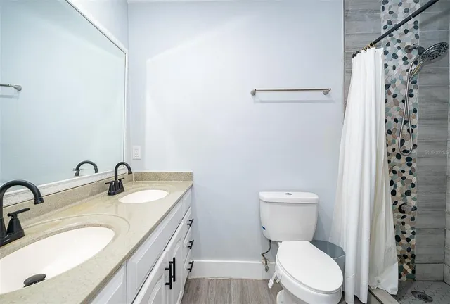 a bathroom with a granite countertop sink a toilet a mirror and shower