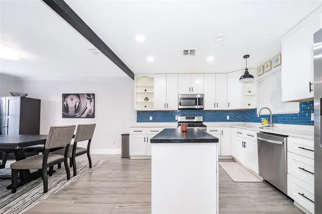 a kitchen with cabinets a sink a counter top space and stainless steel appliances