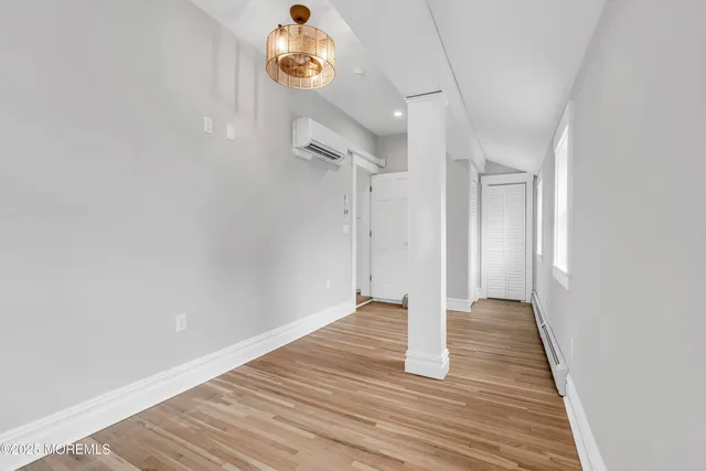 an empty room with wooden floor staircase and windows