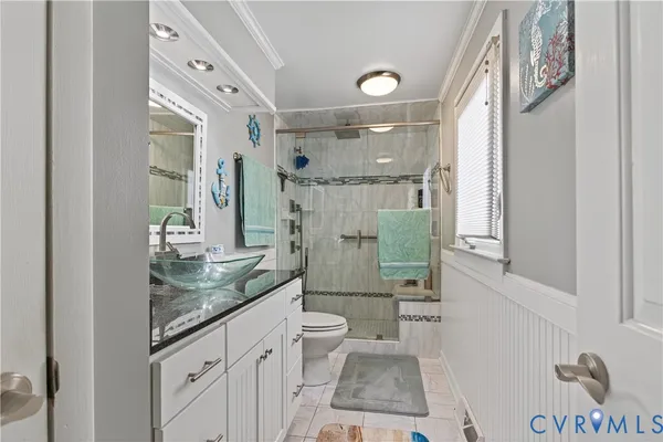 a bathroom with a granite countertop sink a mirror a toilet and shower