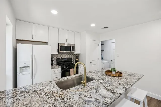 a kitchen with stainless steel appliances kitchen island granite countertop a refrigerator stove oven and white cabinets