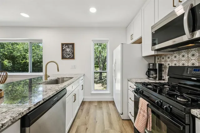 a kitchen with stainless steel appliances granite countertop a stove a sink and a microwave