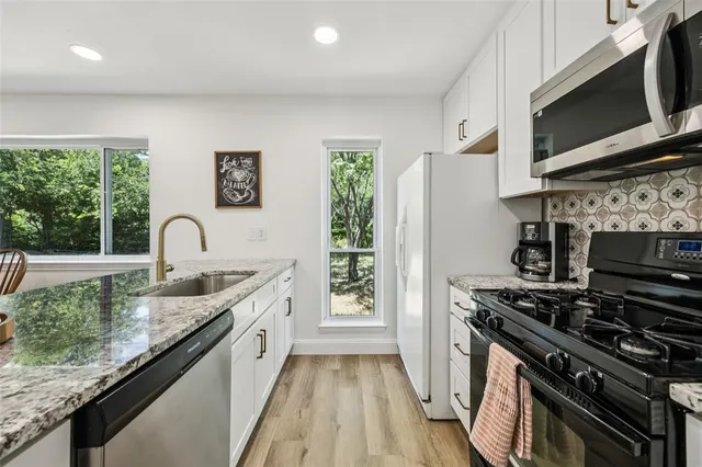 a kitchen with stainless steel appliances granite countertop a stove a sink and a microwave