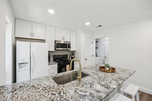 a kitchen with stainless steel appliances kitchen island granite countertop a refrigerator stove oven and a sink