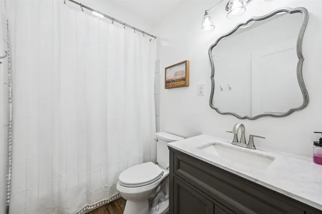 a bathroom with a granite countertop sink and a mirror with toilet