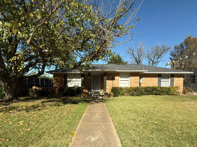 a front view of house with yard and trees in the background