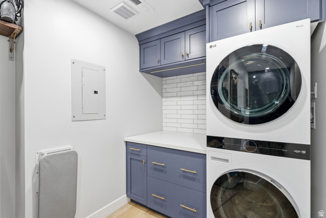 7935 Mustang Loop Road Park City, UT 84098 - Photo 29 of 60 Laundry area featuring a stacked washer and dryer, custom blue cabinetry with brass hardware, white subway tile backsplash, and a white countertop
