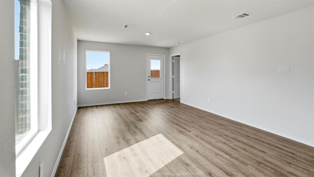 3535 Spring Time Street Forney, TX 75126 - Photo 7 of 23 Spacious room featuring wood-finish flooring, light gray wall paint, and white baseboards