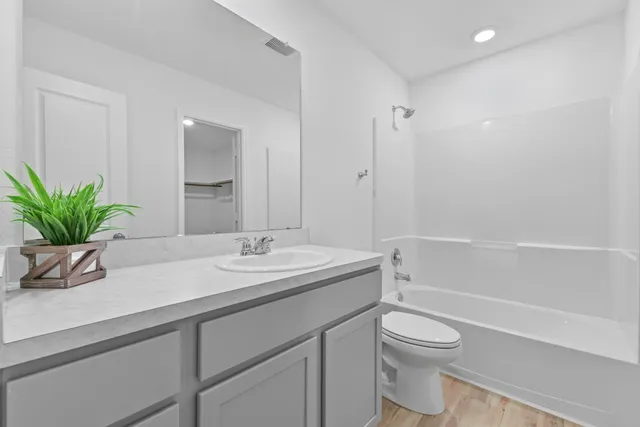 a bathroom with a granite countertop sink a toilet a mirror and shower