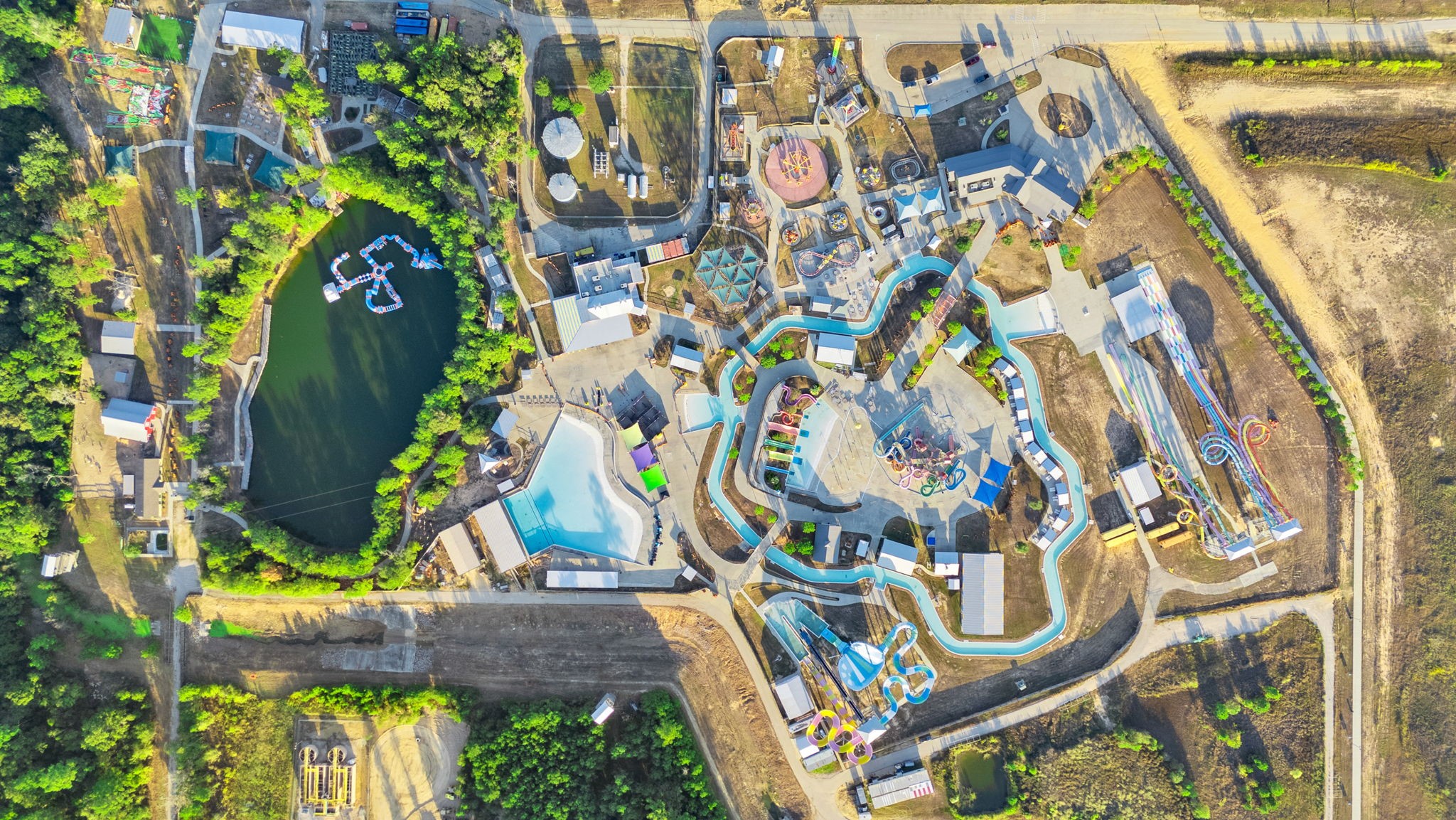 22156 Juniper Crossing Drive New Caney, TX 77357 - Photo 45 of 47 This aerial photo showcases the Big River Water Park, featuring winding water slides, pools, and a small lake surrounded by lush greenery. It's a vibrant recreational area perfect for family fun and outdoor activities. Every Household gets 2 FREE Annual Season Passes with their HOA dues when you purchase the property.