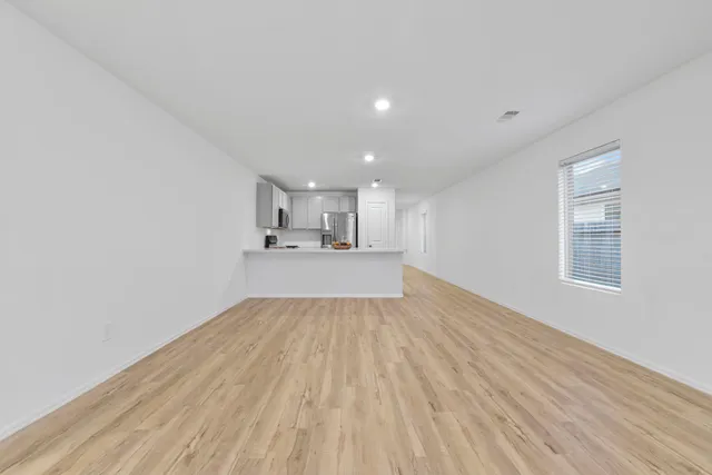 a view of empty room with wooden floor and window