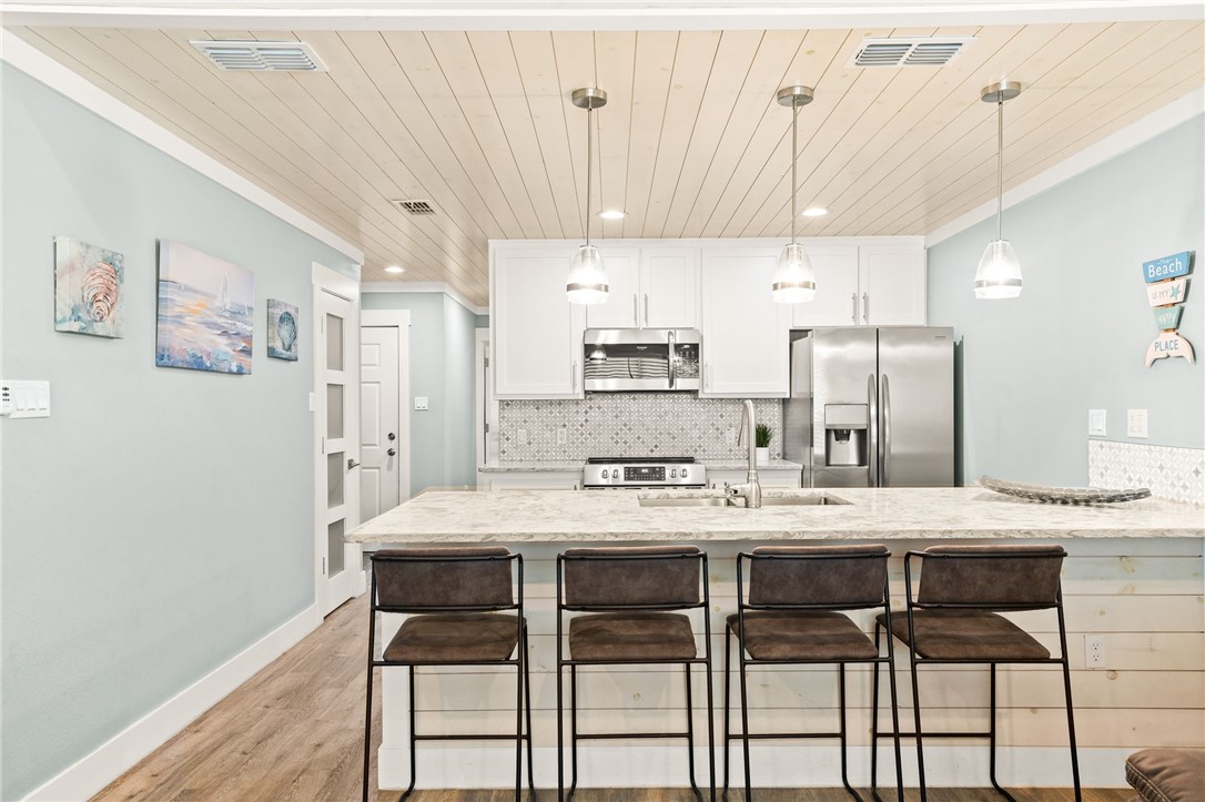 715 Beach Access Road, Unit 1005 Port Aransas, TX 78373 - Photo 8 of 28 a large kitchen with a table chairs refrigerator and microwave