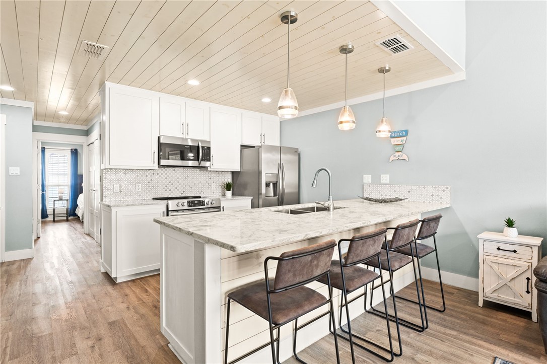 715 Beach Access Road, Unit 1005 Port Aransas, TX 78373 - Photo 9 of 28 a kitchen with kitchen island a stove a table and chairs in it