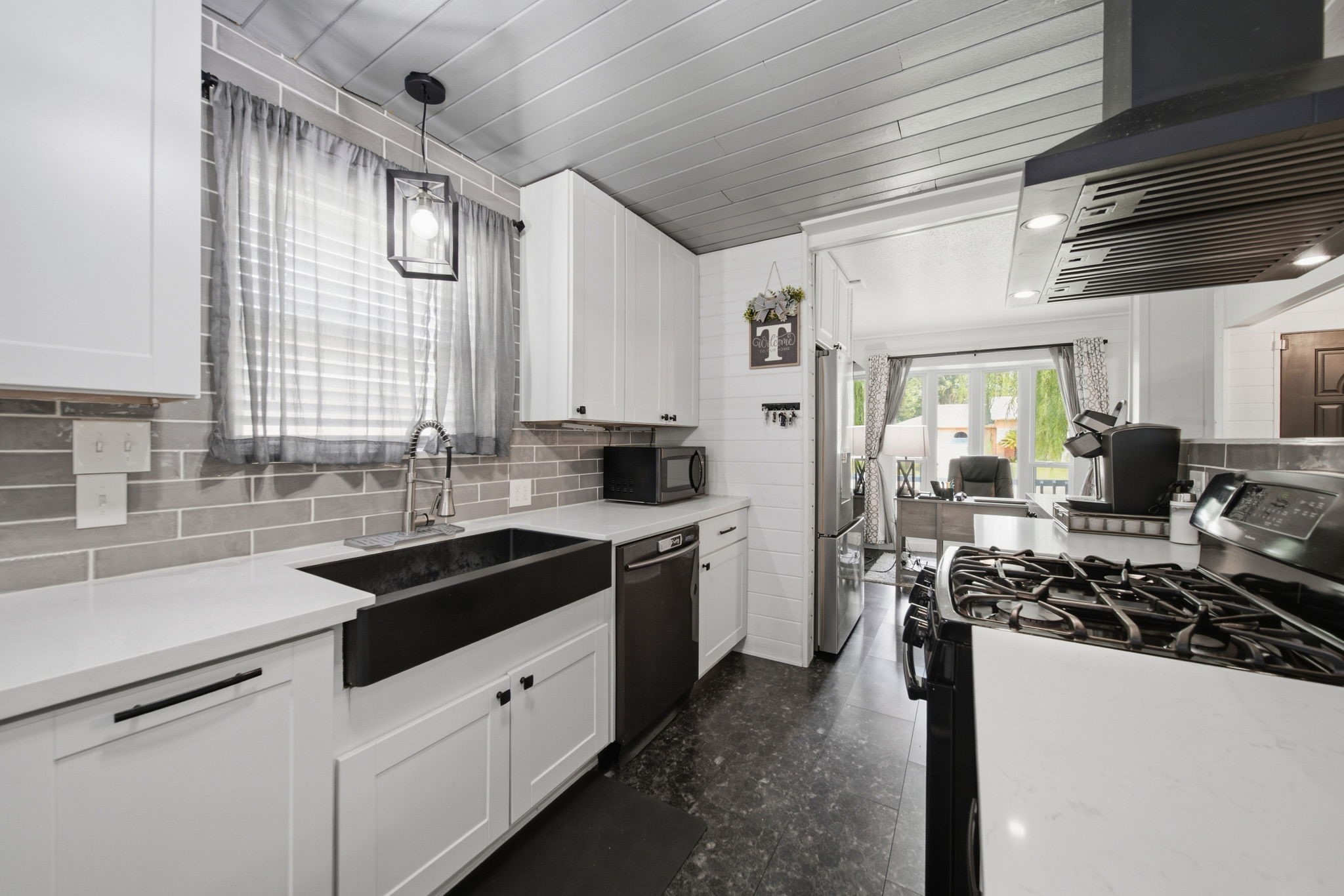 19519 Ricelake Lane Houston, TX 77084 - Photo 10 of 47 Sleek galley kitchen featuring modern appliances, a large farmhouse sink, and elegant white cabinetry. The open layout leads to a bright dining area with ample natural light.