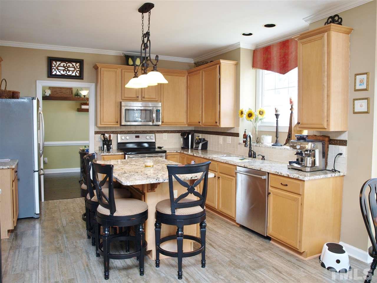 12009 Shavenrock Place Raleigh, NC 27613 - Photo 12 of 30 a kitchen with a dining table chairs sink and cabinets