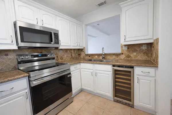 a kitchen with granite countertop white cabinets and stainless steel appliances