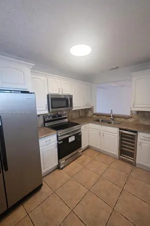 a kitchen with granite countertop a refrigerator and white cabinets