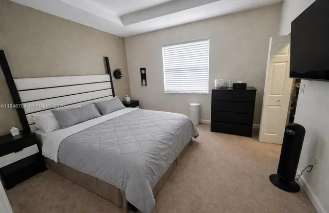 a bedroom with a bed tv and a window