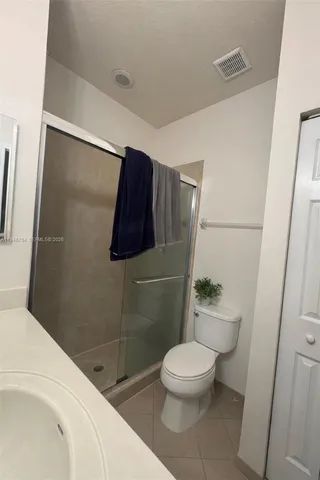 a white toilet sitting next to a bathroom sink and a shower