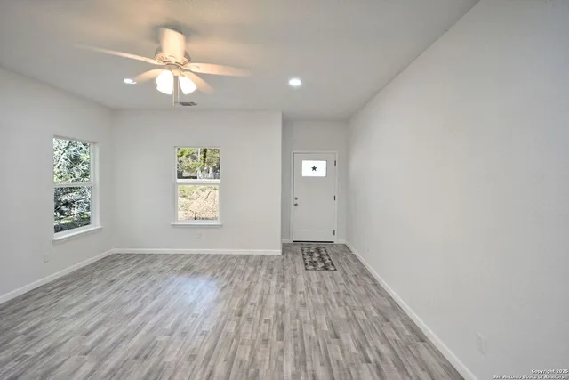 a view of an empty room with a window and wooden floor