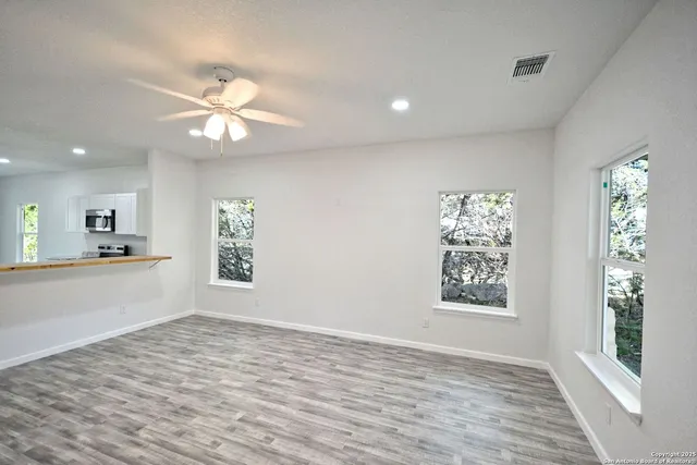 an empty room with a window and ceiling fan