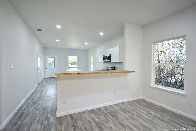 a kitchen with stainless steel appliances a stove top oven a sink dishwasher and a refrigerator with wooden floor