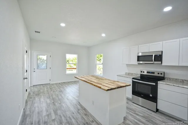 a kitchen with stainless steel appliances granite countertop a stove a sink and a microwave