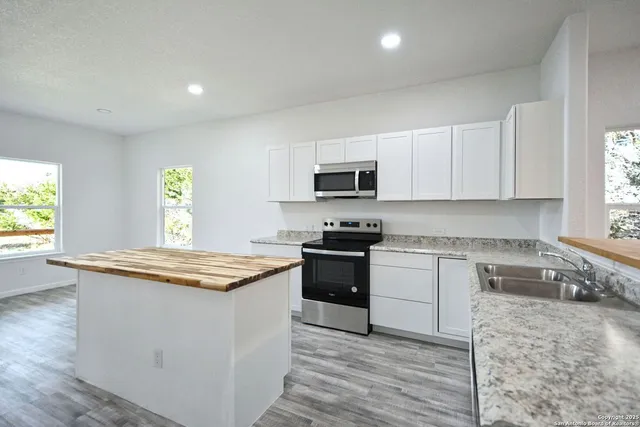 a view of a big room with wooden floor and a kitchen