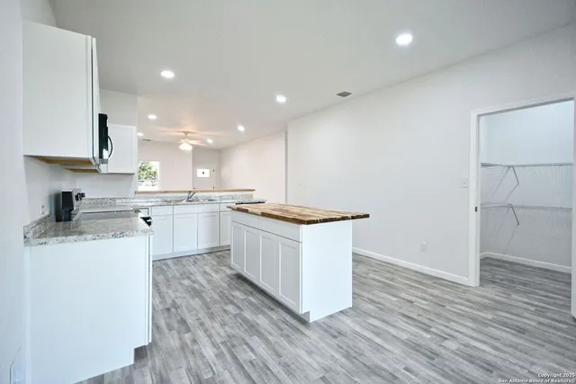 a kitchen with stainless steel appliances granite countertop a stove top oven a sink dishwasher and a refrigerator with wooden floor