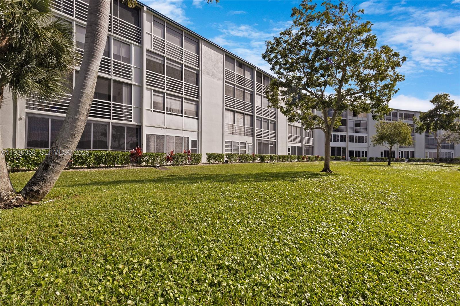 3030 Lincoln B, Unit 3030 Boca Raton, FL 33434 - Photo 23 of 25 a view of a building with a big yard and large trees