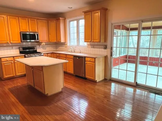 a large kitchen with stainless steel appliances granite countertop a stove a sink and a microwave